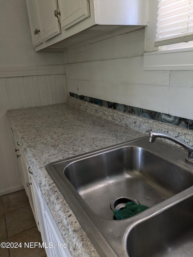 interior details featuring light stone counters, dark tile patterned floors, and sink