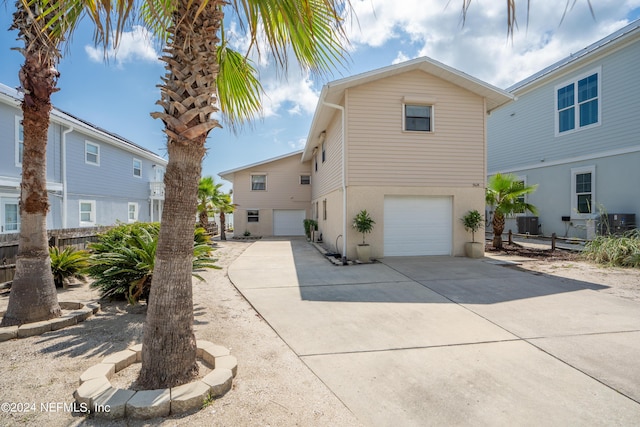 view of front of property with a garage, concrete driveway, cooling unit, and stucco siding