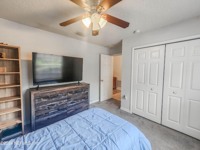 bedroom featuring a textured ceiling, ceiling fan, light carpet, and a closet