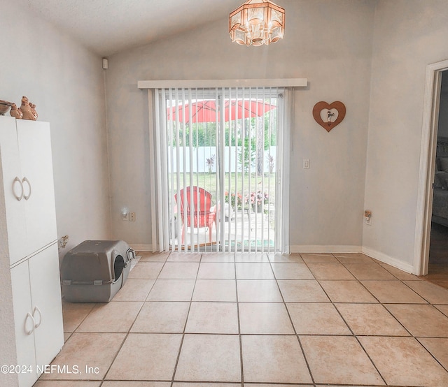 unfurnished dining area featuring light tile patterned floors, lofted ceiling, and a notable chandelier