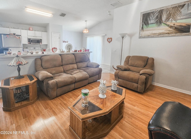 living room with light hardwood / wood-style floors, lofted ceiling, and a textured ceiling