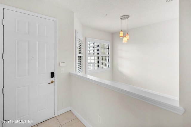 doorway with light tile patterned flooring and a textured ceiling