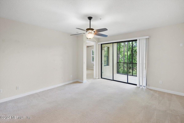 empty room with ceiling fan, light colored carpet, and a textured ceiling