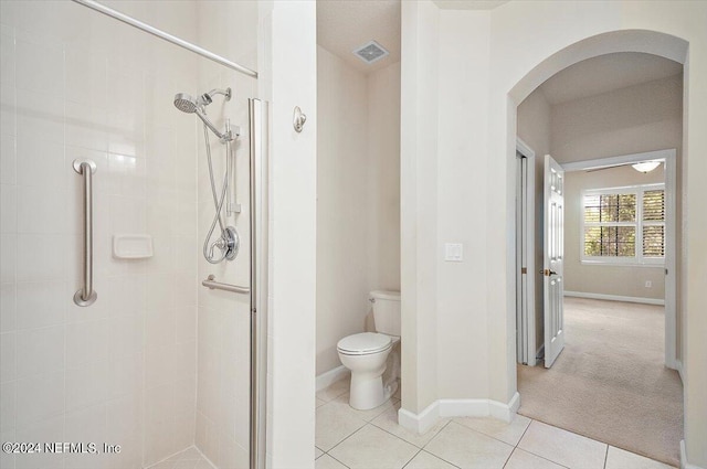 bathroom featuring tile patterned flooring, toilet, and a shower with door