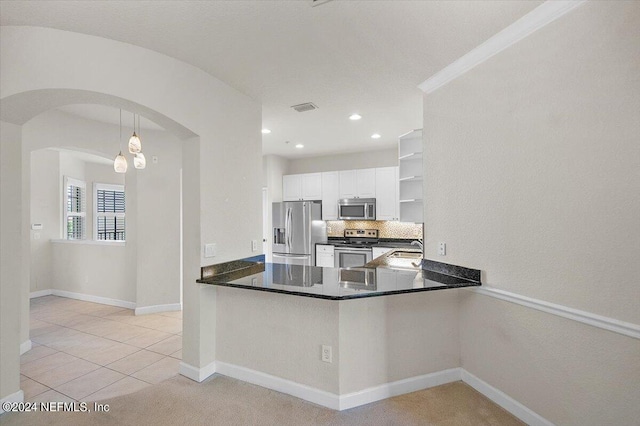 kitchen with hanging light fixtures, kitchen peninsula, appliances with stainless steel finishes, light tile patterned flooring, and white cabinetry