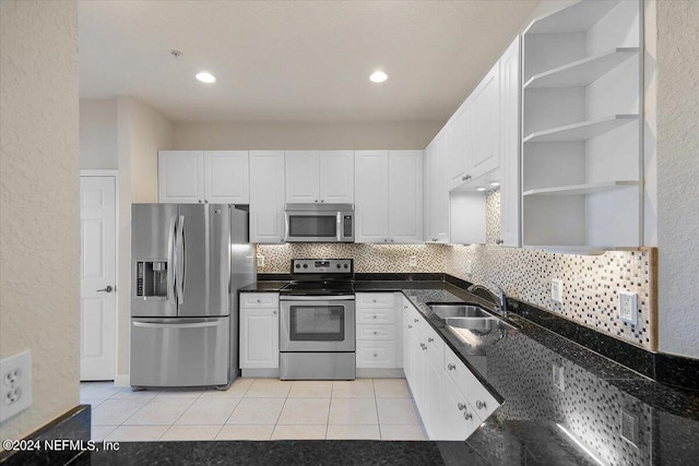 kitchen with sink, stainless steel appliances, light tile patterned floors, backsplash, and white cabinets