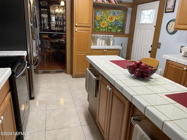 kitchen with tile countertops, black electric range, and light tile patterned floors