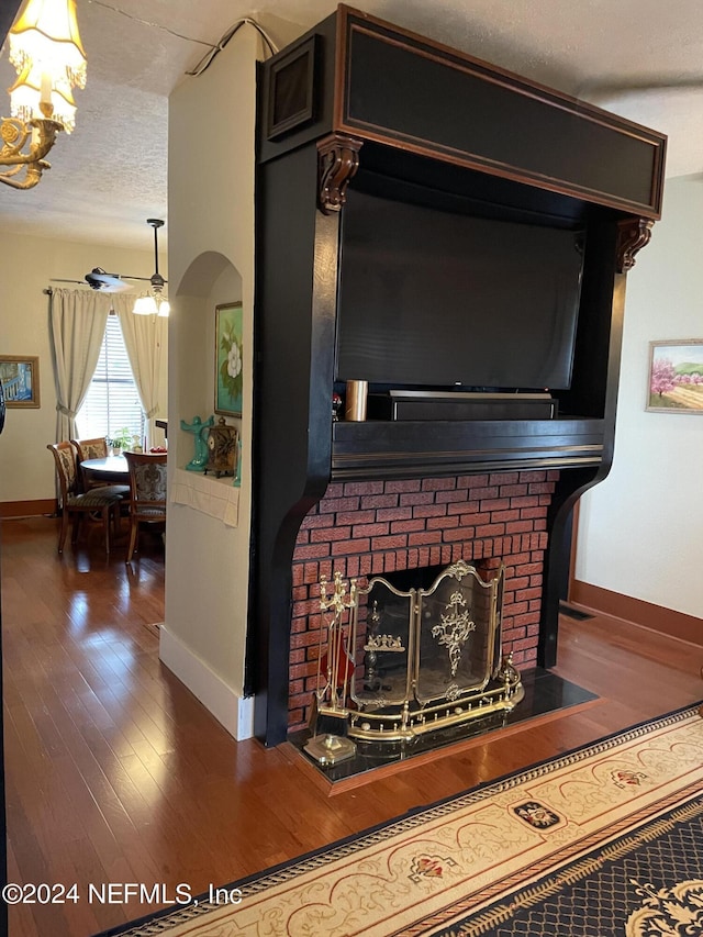 room details with a brick fireplace, hardwood / wood-style flooring, a chandelier, and a textured ceiling