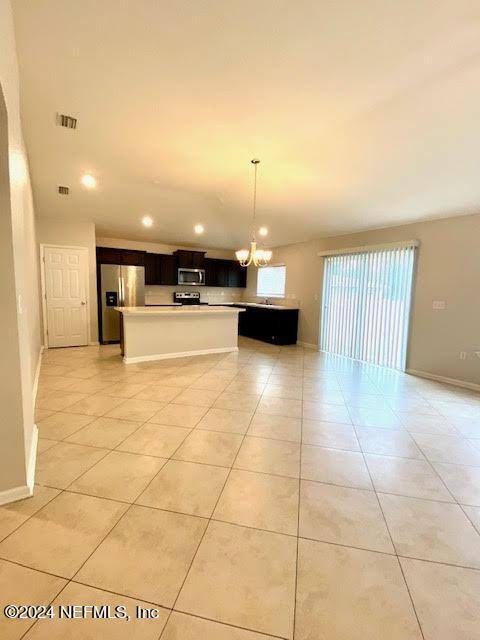 kitchen featuring appliances with stainless steel finishes, a center island, light tile patterned floors, and a notable chandelier