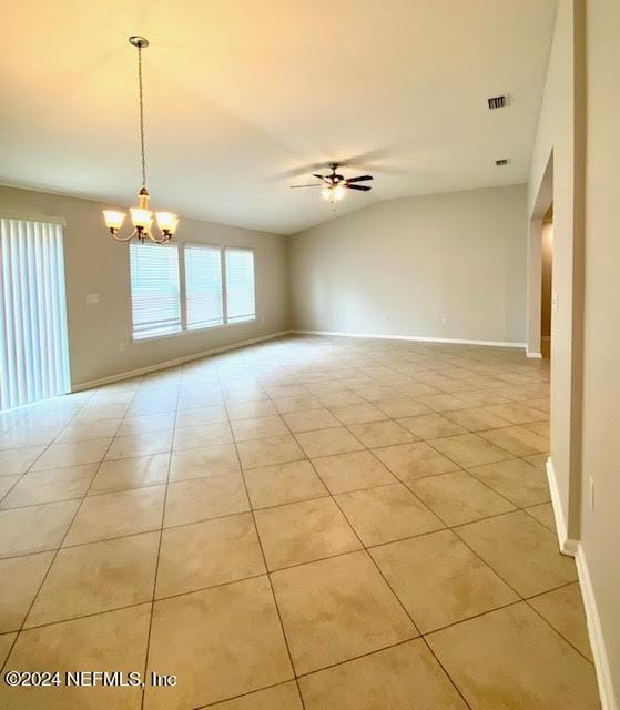 tiled spare room with lofted ceiling and ceiling fan with notable chandelier