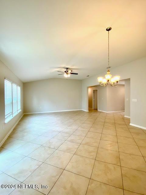 unfurnished room with ceiling fan with notable chandelier and light tile patterned floors