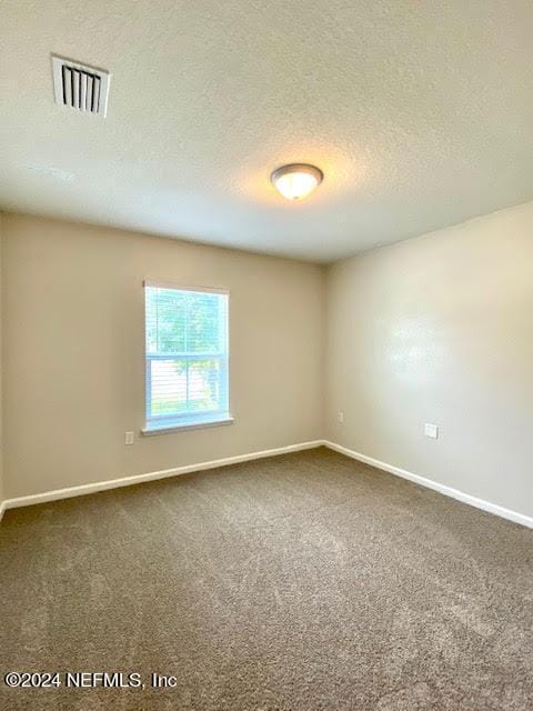 carpeted empty room with a textured ceiling