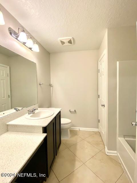 full bathroom with vanity, tile patterned flooring, toilet, a textured ceiling, and shower / bathtub combination