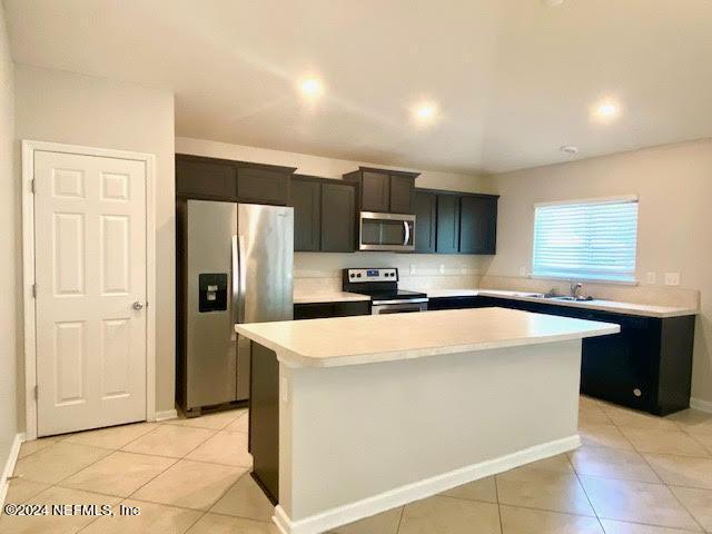 kitchen featuring sink, a kitchen island, stainless steel appliances, and light tile patterned floors