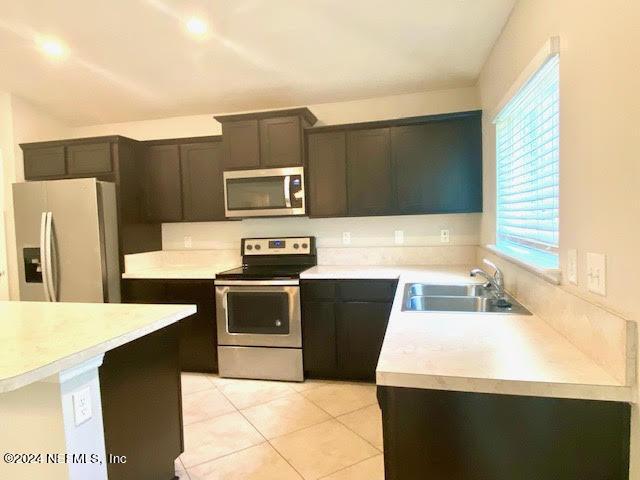 kitchen with plenty of natural light, light tile patterned floors, sink, and appliances with stainless steel finishes