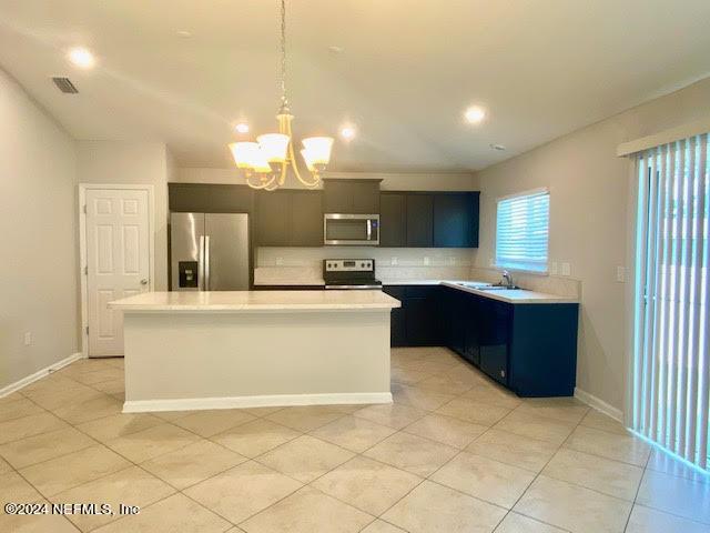 kitchen featuring a center island, hanging light fixtures, an inviting chandelier, light tile patterned floors, and appliances with stainless steel finishes