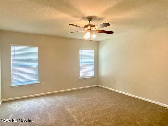 empty room with ceiling fan and carpet