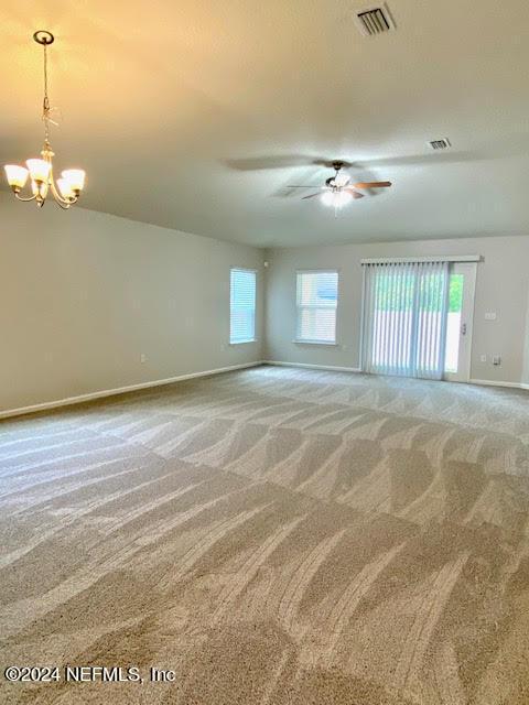 spare room featuring carpet and ceiling fan with notable chandelier