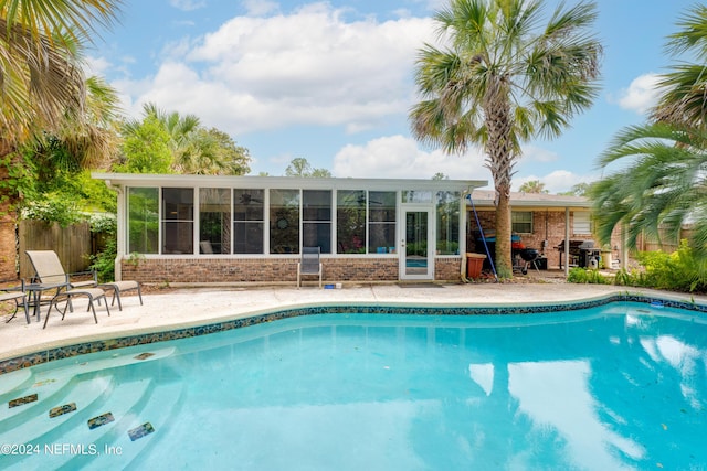 view of swimming pool featuring a sunroom and a patio area