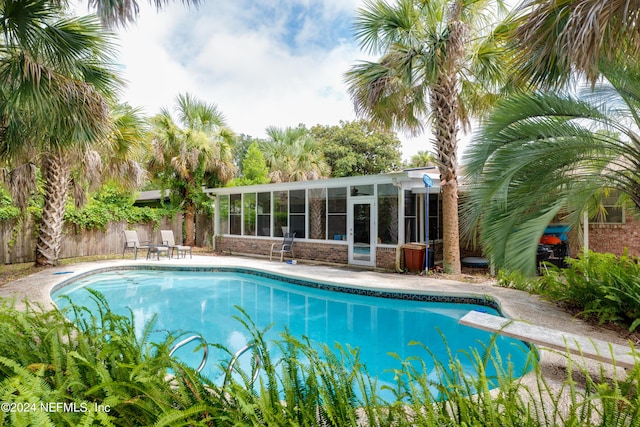 view of swimming pool featuring a diving board and a sunroom