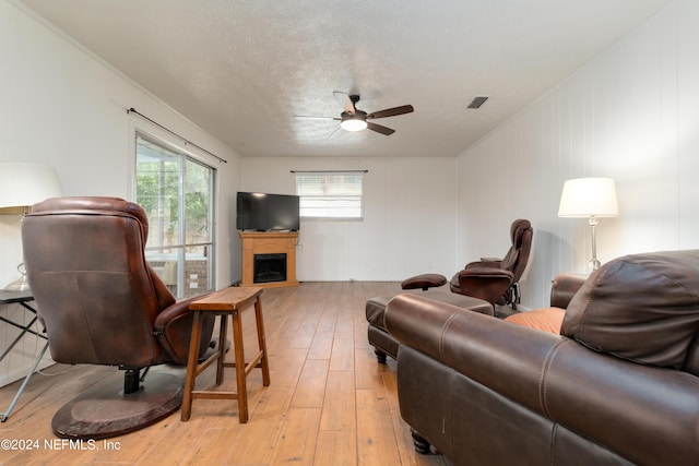 living room with ceiling fan, a textured ceiling, and light hardwood / wood-style flooring