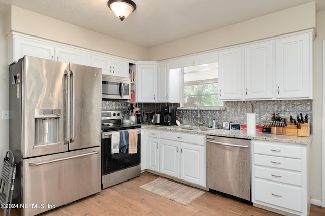 kitchen with sink, light stone countertops, tasteful backsplash, white cabinetry, and stainless steel appliances