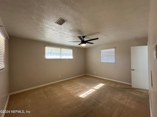 carpeted empty room featuring ceiling fan and a textured ceiling