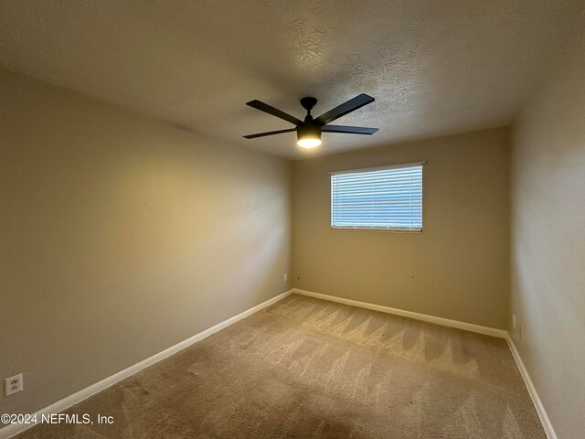 carpeted empty room featuring a textured ceiling