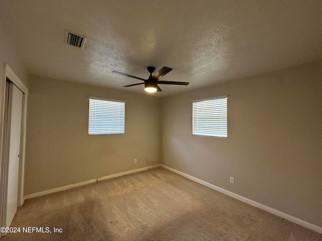 empty room featuring carpet flooring, ceiling fan, and a textured ceiling