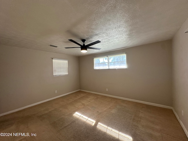 carpeted empty room with ceiling fan and a textured ceiling