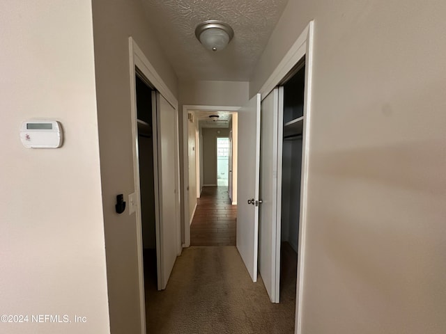 hallway featuring carpet and a textured ceiling