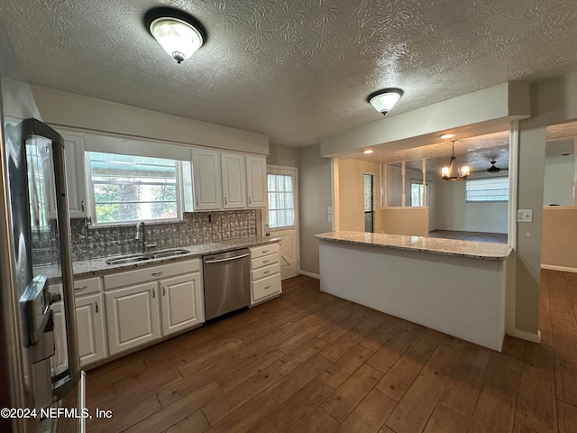 kitchen featuring pendant lighting, sink, stainless steel dishwasher, tasteful backsplash, and white cabinetry