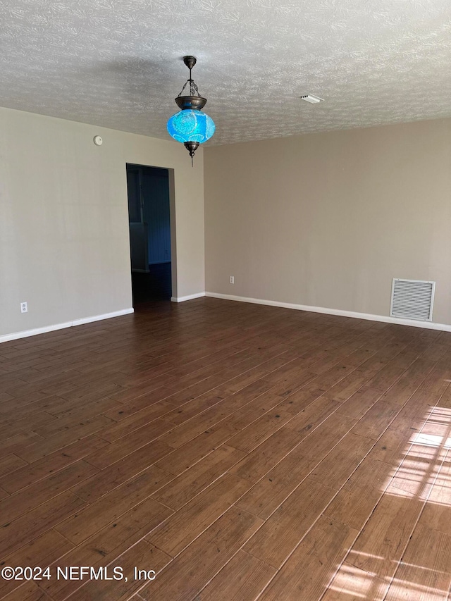 empty room with a textured ceiling and dark wood-type flooring