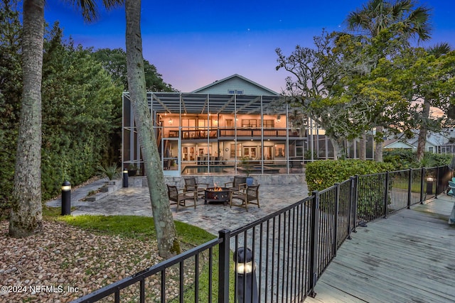 deck at dusk featuring a patio and glass enclosure