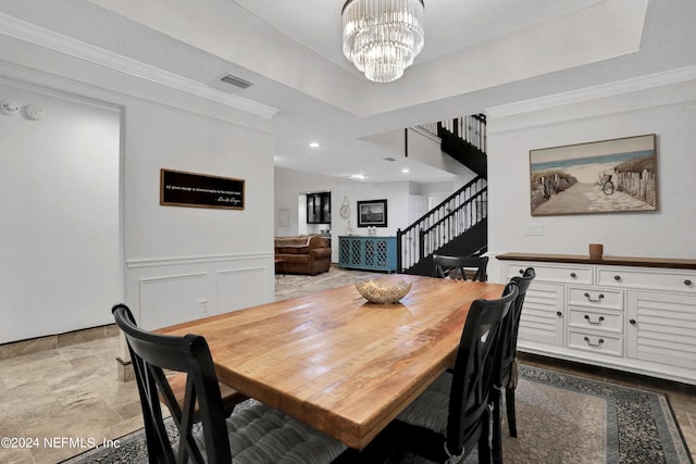 dining area featuring visible vents, wainscoting, ornamental molding, an inviting chandelier, and stairs