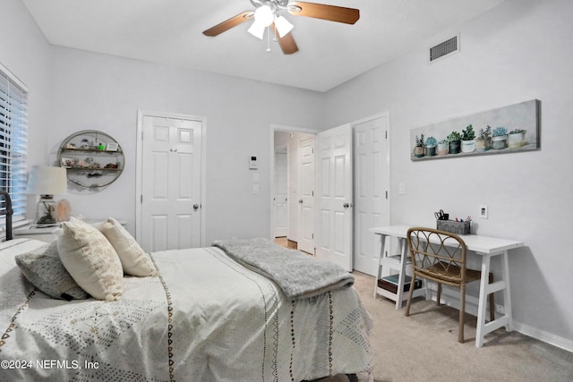 bedroom with ceiling fan, visible vents, baseboards, and light colored carpet