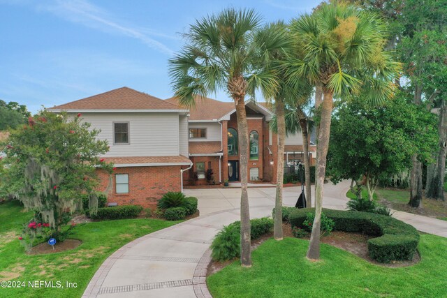 view of front facade with driveway, a front lawn, and brick siding