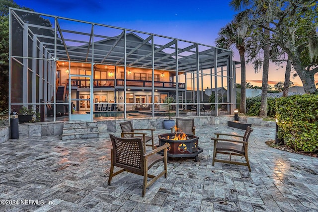 patio terrace at dusk featuring a lanai and a fire pit