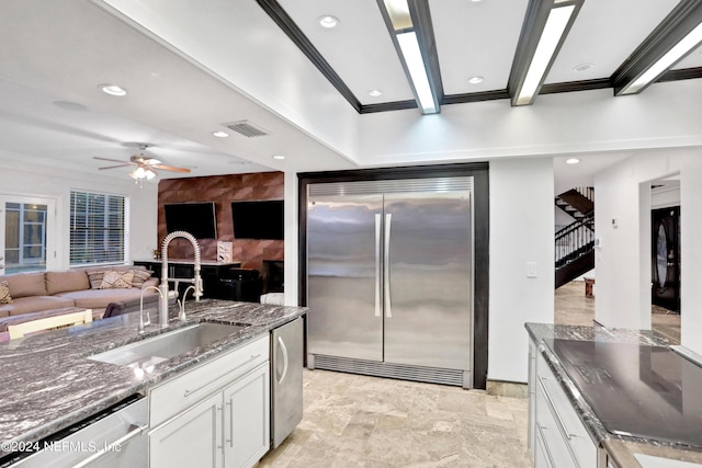 kitchen with visible vents, dark stone counters, appliances with stainless steel finishes, white cabinetry, and a sink