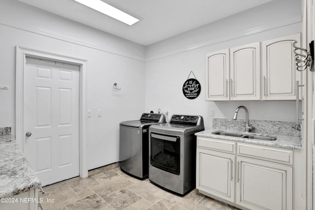 laundry area with stone finish flooring, independent washer and dryer, a sink, and cabinet space