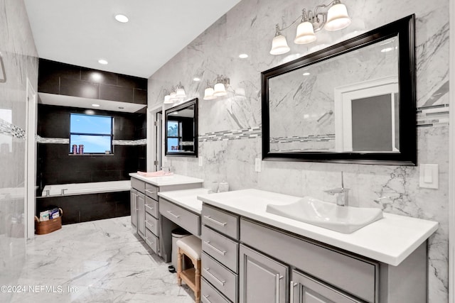 full bath with marble finish floor, two vanities, a garden tub, and a sink