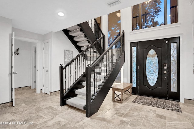 foyer entrance with stone finish flooring, stairway, visible vents, and baseboards