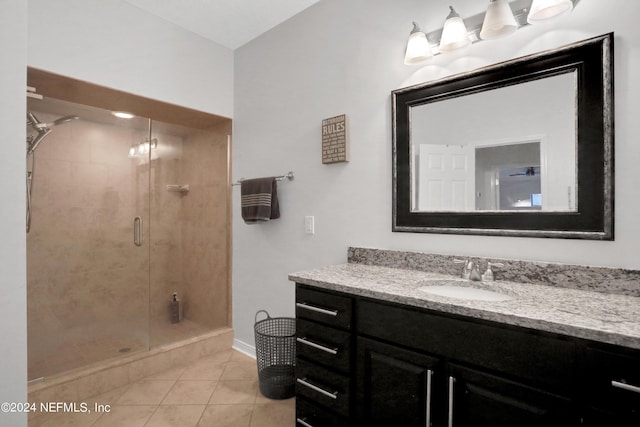 full bath featuring tile patterned flooring, a shower stall, vanity, and baseboards