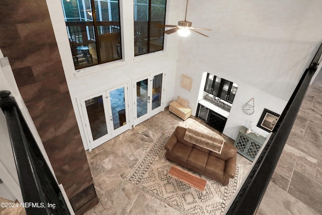 living area featuring stone finish floor, ceiling fan, and a high ceiling