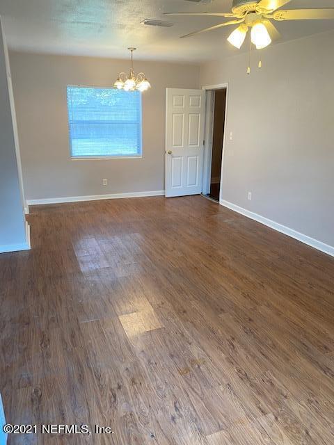 spare room with ceiling fan with notable chandelier and dark wood-type flooring