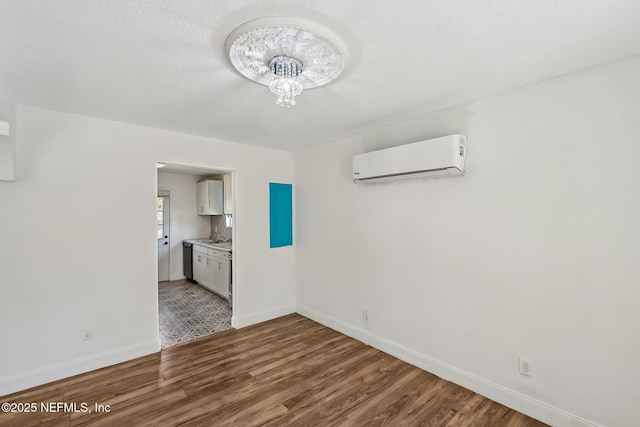 interior space with an inviting chandelier, a wall mounted air conditioner, baseboards, and wood finished floors