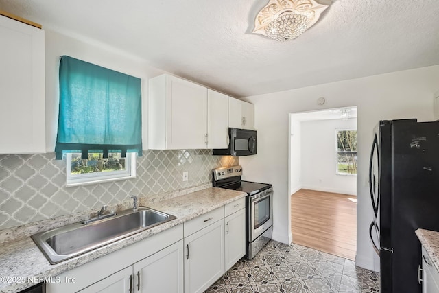 kitchen featuring a healthy amount of sunlight, white cabinetry, black appliances, and a sink