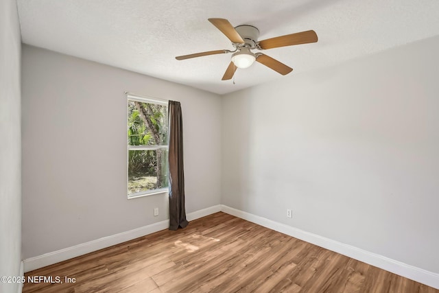 unfurnished room featuring ceiling fan, baseboards, a textured ceiling, and light wood-style flooring