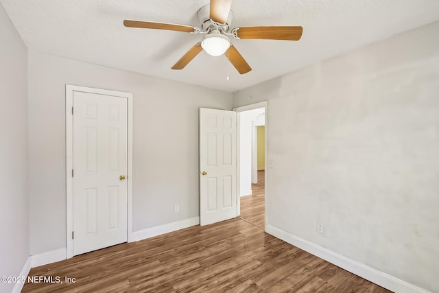 unfurnished bedroom with a ceiling fan, wood finished floors, and baseboards