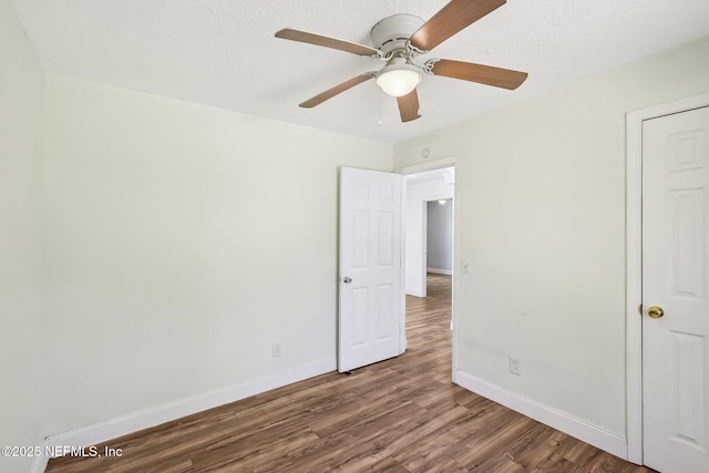 interior space with a ceiling fan, wood finished floors, baseboards, and a textured ceiling